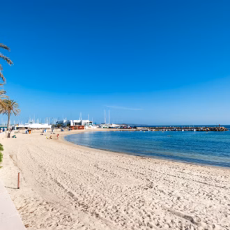 Cala Estancia beach with calm turquoise waters and sunbeds.