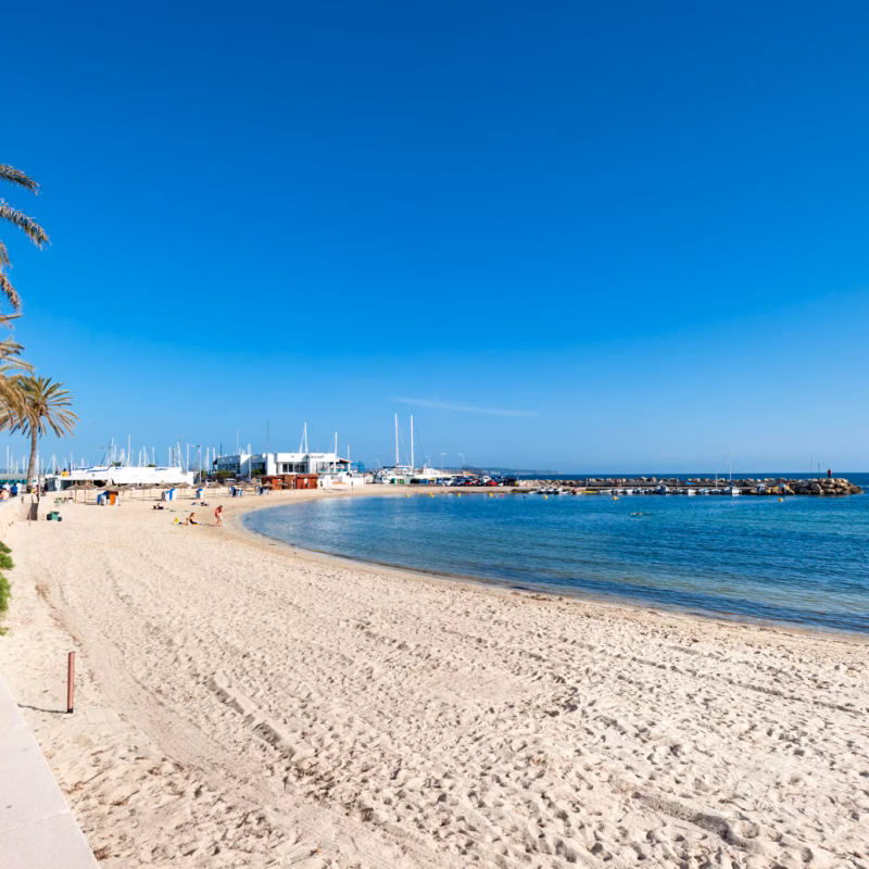 Cala Estancia beach with calm turquoise waters and sunbeds.