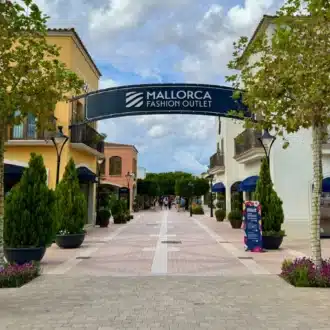 Exterior of Mallorca Fashion Outlet with shoppers and open-air walkways.