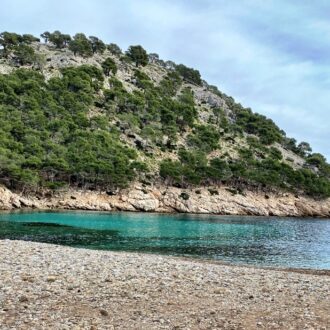 Pebble cove and clear turquoise water at Cala Murta on the Formentor peninsula