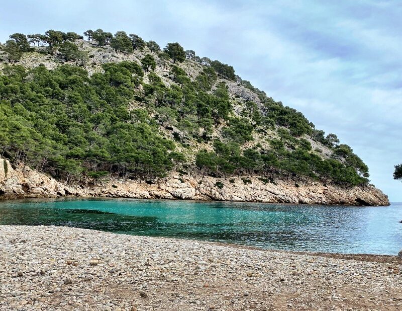 Pebble cove and clear turquoise water at Cala Murta on the Formentor peninsula