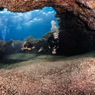 Divers hovering above a rocky reef with clear Mediterranean water off Mallorca